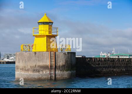 Tour de phare jaune sur un brise-lames en béton, entrée au port principal de Reykjavik, Islande Banque D'Images