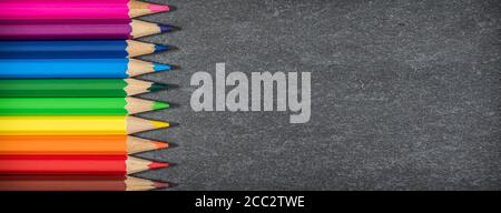 Bordure des crayons de couleur sur fond noir. Concept scolaire. Banque D'Images