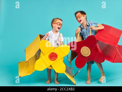 Deux enfants visionnaires heureux imaginent voler dans un avion dans le ciel. Jouer et rire ensemble Banque D'Images