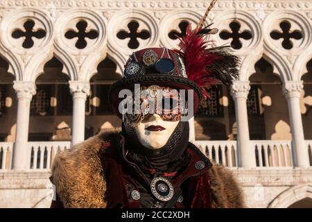 VENISE, ITALIE - 18 JUILLET 2017 : gros plan d'un homme vêtu d'un masque et d'une robe typique du Carnaval de Venise, avec le Palais des Doges en arrière-plan Banque D'Images