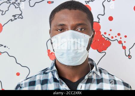 portrait du jeune homme noir dans le masque médical, se tenir en arrière-plan de la carte du monde avec des marques rouges, coronavirus propagation dans le monde entier. covid-19 infe Banque D'Images