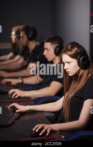 Équipe de joueurs professionnels eSport avec une jeune femme adorable en plein foyer jouant dans des jeux vidéo sur un Cyber Games Tournament. Ils utilisent des micro-casques et des Banque D'Images