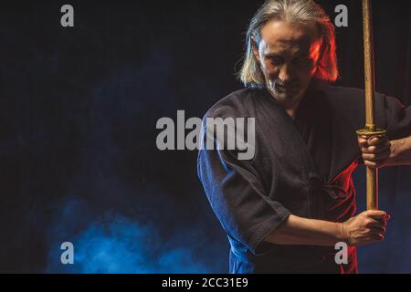 kendo combat guerrier en robe traditionnelle sur fond fumé, avant les compétitions. Homme passionné par l'art martial traditionnel japonais entraînement, puissance. Banque D'Images