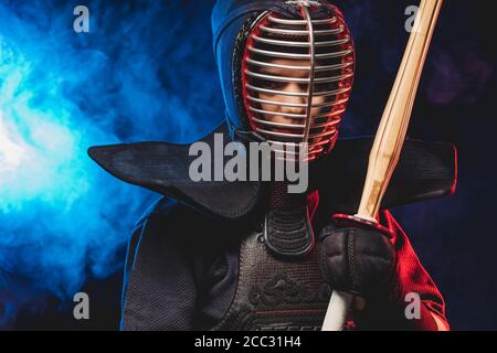 chasseur de kendo confiant dans l'armure pratiquant avec l'épée de bambou, se préparant aux compétitions. samouraï, concept de kendo. espace fumé isolé Banque D'Images