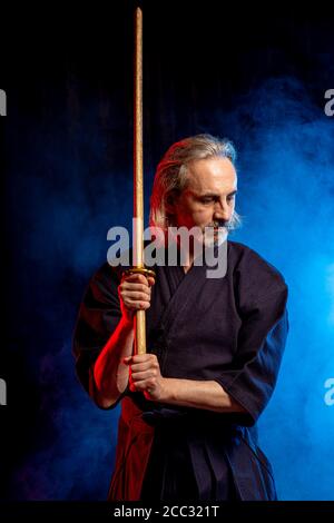 Chasseur kendo mâle caucasien dans le style traditionnel japonais de vêtements, armure de protection, utilisant shinai. Pratiquant le combat isolé sur la pièce fumée Banque D'Images