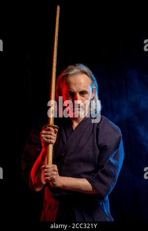 portrait d'un homme caucasien fort kendo combattant avec bokuto. kendo guerrier mâle tenant sabre samouraï katana Banque D'Images