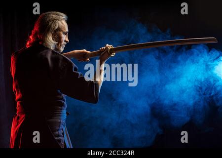 vue latérale sur un chasseur de kendo sérieux et confiant avec shinai dans les mains, homme en robe traditionnelle look côté Banque D'Images