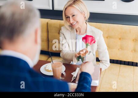 l'homme donne une rose à une blonde belle femme souriante, bonheur, surprise concepts. gros plan photo.célébration concept Banque D'Images