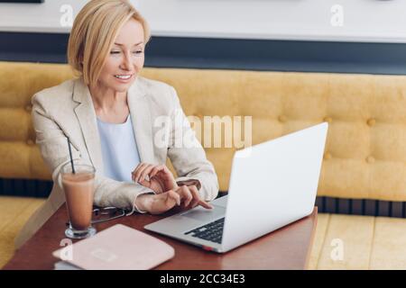 belle femme regardant une vidéo, un film tout en ayant un repos dans le café-restaurant, vue de côté de la photo. femme passant un moment agréable dans le café Banque D'Images