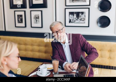 homme intelligent dans un élégant costume violet signalant les erreurs du projet dans le café avec intérieur moderne. gros plan photo. correction concept Banque D'Images