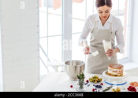 chef féminin talentueux utilisant un sac de pstry pendant la cuisson. gros plan photo. espace de copie . Banque D'Images