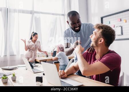 Une attention sélective aux hommes d'affaires multiculturels qui se mettent à boter tout en travaillant au bureau Banque D'Images