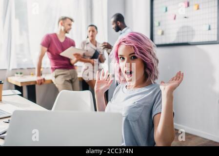 Mise au point sélective d'une femme d'affaires excitée regardant la caméra pendant son travail au bureau Banque D'Images