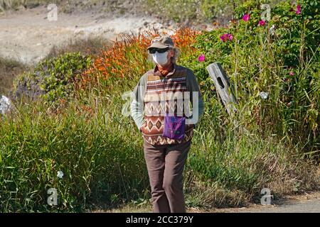 Une femme portant un visage couvrant marche le long d'un chemin sur la côte de l'océan Pacifique près de la ville de Yachats, Oregon. Banque D'Images