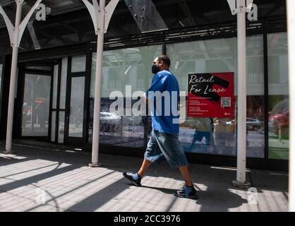 17 août 2020 : une affiche de vente au détail pour location se trouve dans la fenêtre d'un magasin sur la 7e avenue, tandis qu'une personne se trouve dans un masque d'EPI et passe devant les magasins de détail qui luttent en raison de la pandémie Covid-19 à Manhattan, New York. Crédit obligatoire : Kostas Lymperopoulos/CSM Banque D'Images