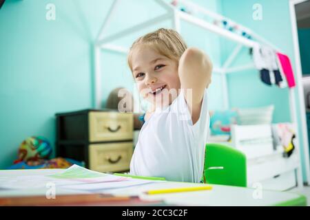 Adorable petite fille dessin avec des crayons à la maison assis à la table. Enfant créatif assis dans une pièce apprenant à dessiner. Petite fille faisant Banque D'Images