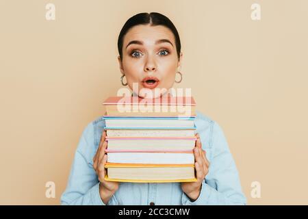 surpris étudiant en chemise denim avec des livres isolés sur beige Banque D'Images