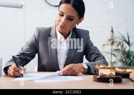 orientation sélective de l'avocat de brunette dans l'assurance de signature de vêtements officiels documents au bureau Banque D'Images