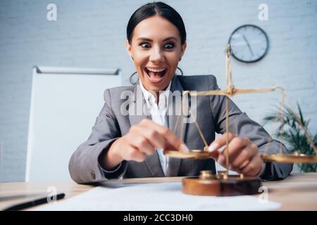 attention sélective de l'avocat excité dans l'habillement formel touchant les balances au bureau Banque D'Images