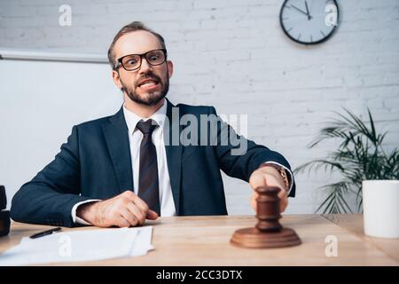 accent sélectif du juge barbu dans la tenue de lunettes et de costume gavel à proximité de documents Banque D'Images