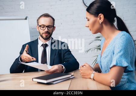 attention sélective de l'avocat barbu dans les lunettes pointant avec la main dans les documents près du client au bureau Banque D'Images