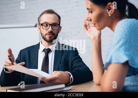 attention sélective de l'avocat barbu dans les lunettes regardant le client lors de la conservation du document au bureau Banque D'Images