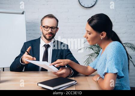 foyer sélectif de la femme pointant du doigt vers le document à proximité avocat barbu en lunettes Banque D'Images