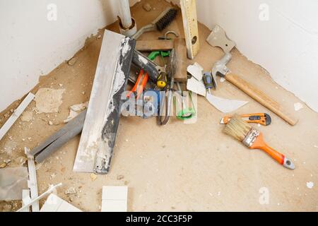 Les outils de construction et de réparation se trouvent sur le sol en béton lors des travaux de réparation à l'aide d'une spatule, d'un marteau, d'un mètre ruban. Pour effectuer des réparations. Mise au point sélective Banque D'Images