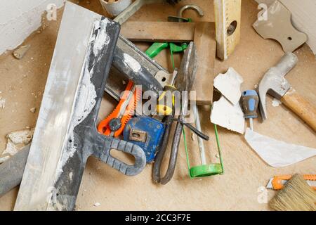 Les outils de construction et de réparation se trouvent sur le sol en béton lors des travaux de réparation à l'aide d'une spatule, d'un marteau, d'un mètre ruban. Pour effectuer des réparations. Mise au point sélective Banque D'Images