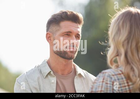 Tête et épaules portrait d'un beau adulte regardant la petite amie tout en appréciant la date romantique à l'extérieur dans la lumière du soleil, espace de copie Banque D'Images
