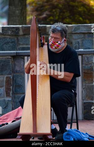 Frederick, MD, USA 08/14/2020: La nouvelle norme due à la pandémie de COVID 19: Un musicien à poil dur gris âgé porte un drapeau du Maryland imprimé fa Banque D'Images