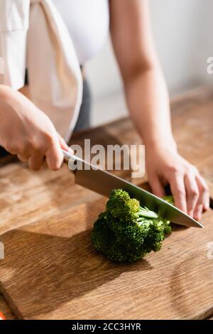 vue rognée d'une femme tayant du brocoli frais sur une planche à découper Banque D'Images