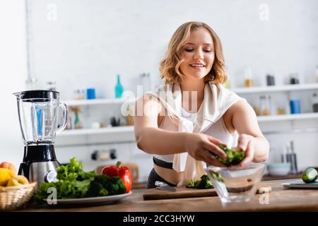 foyer sélectif de la jeune femme mettant le brocoli dans le bol près légumes Banque D'Images