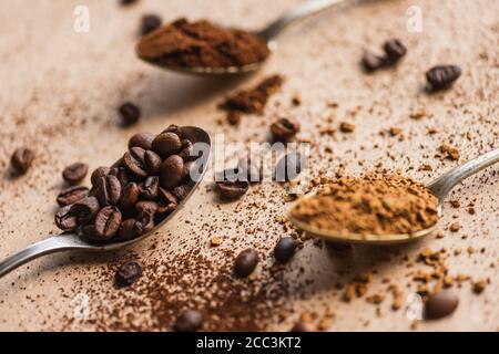 mise au point sélective du café moulu et instantané et des grains de café dans des cuillères sur une surface beige Banque D'Images