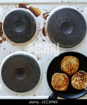 cuisinière sale avec des aliments brûlés et de l'huile de cuisson, poêle avec crêpes sur le dessus Banque D'Images