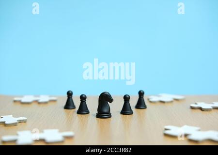 Photo conceptuelle de la stratégie d'affaires - une ligne de cheval pièces d'échecs au milieu d'une armée et d'un puzzle casse-têtes Banque D'Images