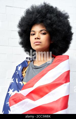 Fière femme africaine se tenir sur fond blanc enveloppé dans le drapeau des états-unis, portrait. Banque D'Images