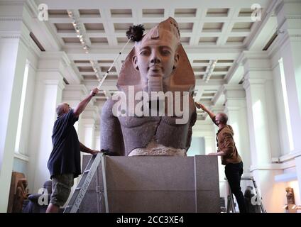 Evan York (à gauche) et Alex Truscott, responsables de la collection, ont dépoussiéré la partie supérieure d'une statue colossale assise du roi Ramsès II (vers 1279-1213 av. J.-C.), dans la galerie de sculptures égyptiennes du British Museum, Londres, alors qu'ils se préparent à rouvrir au public le 27 août après l'enfermement du coronavirus. En prévision de sa réouverture, le British Museum s'est lancé dans le plus grand programme de nettoyage depuis des décennies. Banque D'Images