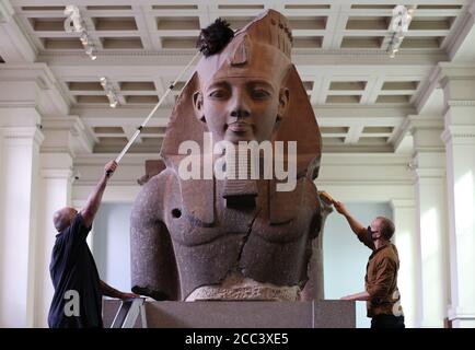 Evan York (à gauche) et Alex Truscott, responsables de la collection, ont dépoussiéré la partie supérieure d'une statue colossale assise du roi Ramsès II (vers 1279-1213 av. J.-C.), dans la galerie de sculptures égyptiennes du British Museum, Londres, alors qu'ils se préparent à rouvrir au public le 27 août après l'enfermement du coronavirus. En prévision de sa réouverture, le British Museum s'est lancé dans le plus grand programme de nettoyage depuis des décennies. Banque D'Images