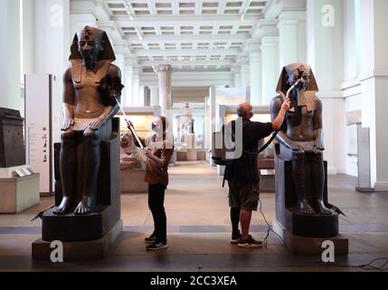 Alex Truscott (à gauche) et Evan York dépoussiérant des statues d'Amenhotep III (vers 1390-1352 av. J.-C.), dans la galerie de sculptures égyptiennes du British Museum, Londres, alors qu'ils se préparent à rouvrir au public le 27 août après le confinement du coronavirus. En prévision de sa réouverture, le British Museum s'est lancé dans le plus grand programme de nettoyage depuis des décennies. Banque D'Images