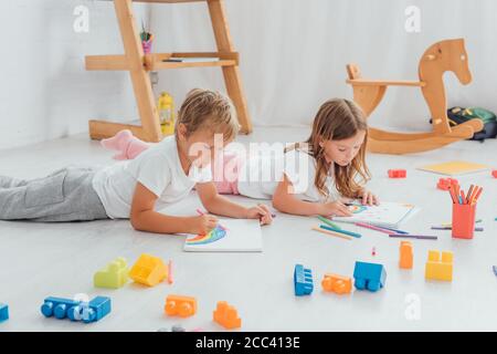 frère et sœur en pyjama couchés à l'étage près du bâtiment blocs et dessin avec des stylos feutre Banque D'Images