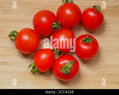 Tomates maison rouge vif fraîchement cueillies, Variety Mountain Magic, posées sur une planche de bois Banque D'Images