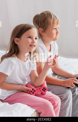 KIEV, UKRAINE - 21 JUILLET 2020: Foyer sélectif de fille tenant joystick près concentré frère jouant le jeu vidéo Banque D'Images