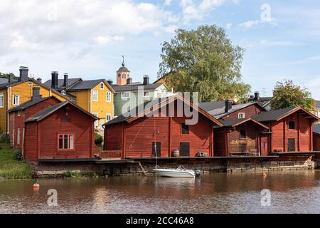 Vieux bâtiments de stockage en ocre rouge sur la rive de Porvoonjoki et maisons en bois de la vieille ville en arrière-plan à Porvoo, en Finlande Banque D'Images