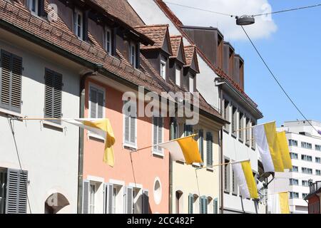 Drapeau de la cité du Vatican qui s'affiche par les fenêtres des vieilles maisons traditionnelles près de Freiburg Minster dans le centre-ville de Fribourg-en-Brisgau, en Allemagne. Banque D'Images