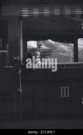 1950s, historique, une femme assise à l'intérieur d'une calèche suisse, penchée d'une fenêtre ouverte, Alpes suisses, Suisse. Le nombre 3 en chiffres romains est en lettres sur le train à faire Banque D'Images