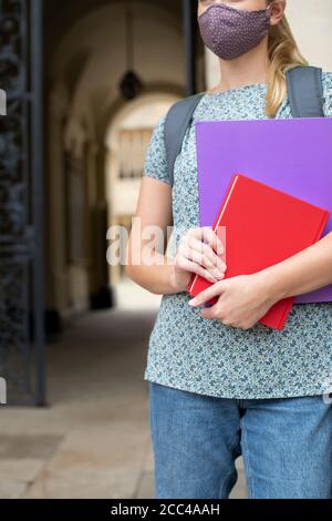 Gros plan d'une étudiante féminine debout à l'extérieur du collège ou de l'université Bâtiment portant un masque facial pendant la pandémie Covid-19 Banque D'Images