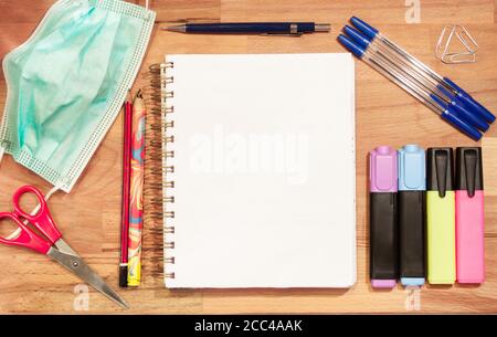 Articles de papeterie avec carnet vierge et masque de protection sur une surface en bois Banque D'Images