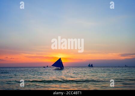 Bateau philippin traditionnel à l'idyllique plage de sable blanc de l'île Boracay à Philiberines au coucher du soleil Banque D'Images