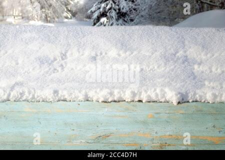 Un épais chapeau de neige sur une boîte en bois sur le fond d'une forêt d'hiver avec la lumière du soleil. Bannière du nouvel an avec une ambiance de Noël. Banque D'Images